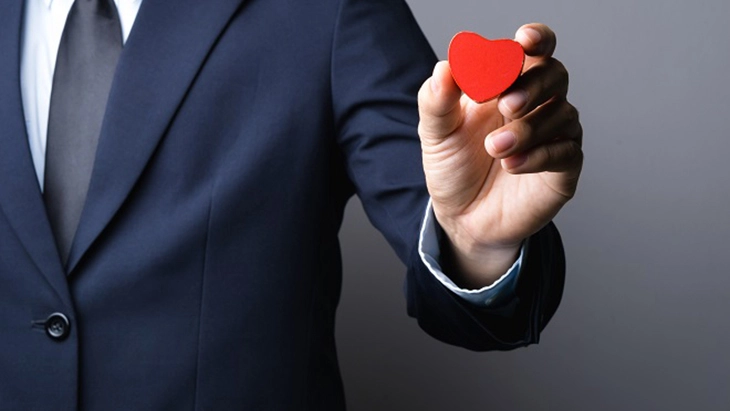 Close up of hand holding small red heart-shaped object